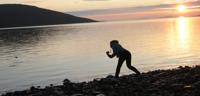 the gf skimming stones on loch broom.  She's in silhouette against an ornage sky with the setting sun